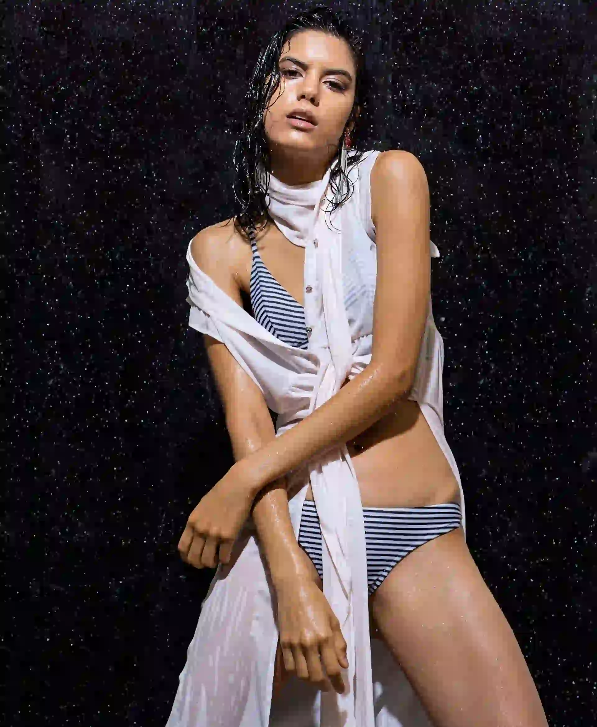 Camisa de gasa con tajos y botones en la pechera ($ 1.590, Wanama), bikini rayada con corpiño armado y bombacha de media cola ($ 1.422, Luz de Mar) y aros de piedras con strass (Los Vados del Isen). Foto: Juan Jauregui/ Para Ti