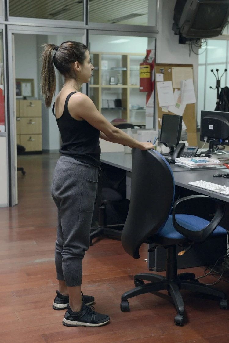 Estiramiento de la espalda. 1. De pie, apoyá las manos sobre el respaldo de la silla