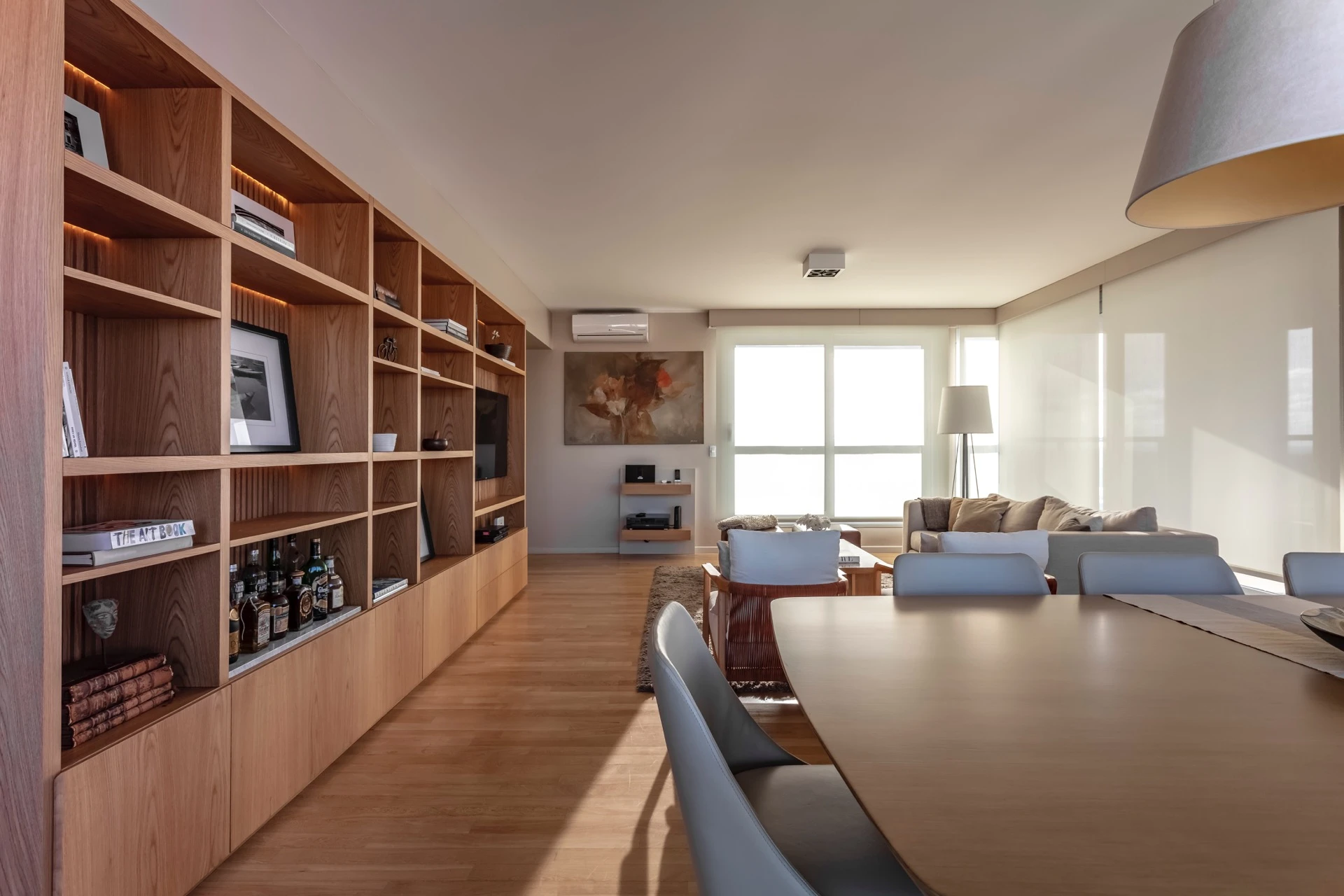 Living y comedor comparten un mismo y gran ambiente, y por ende una misma estética. El gran mueble de roble que es biblioteca y bar a la vez, los une.