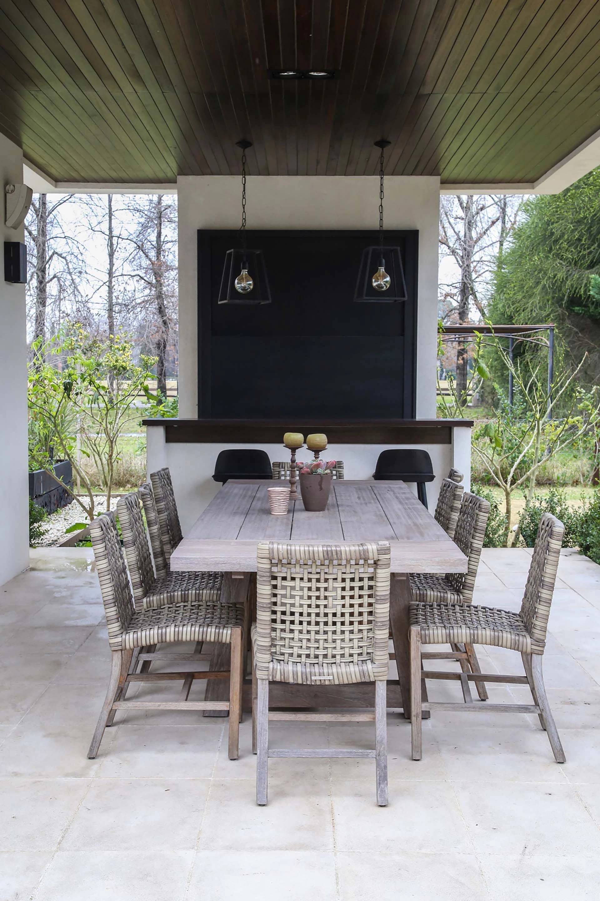 Junto a la parrilla, el comedor de exteriores ocupa un apéndice de la construcción  enmarcado a ambos lados por el cuidado jardín