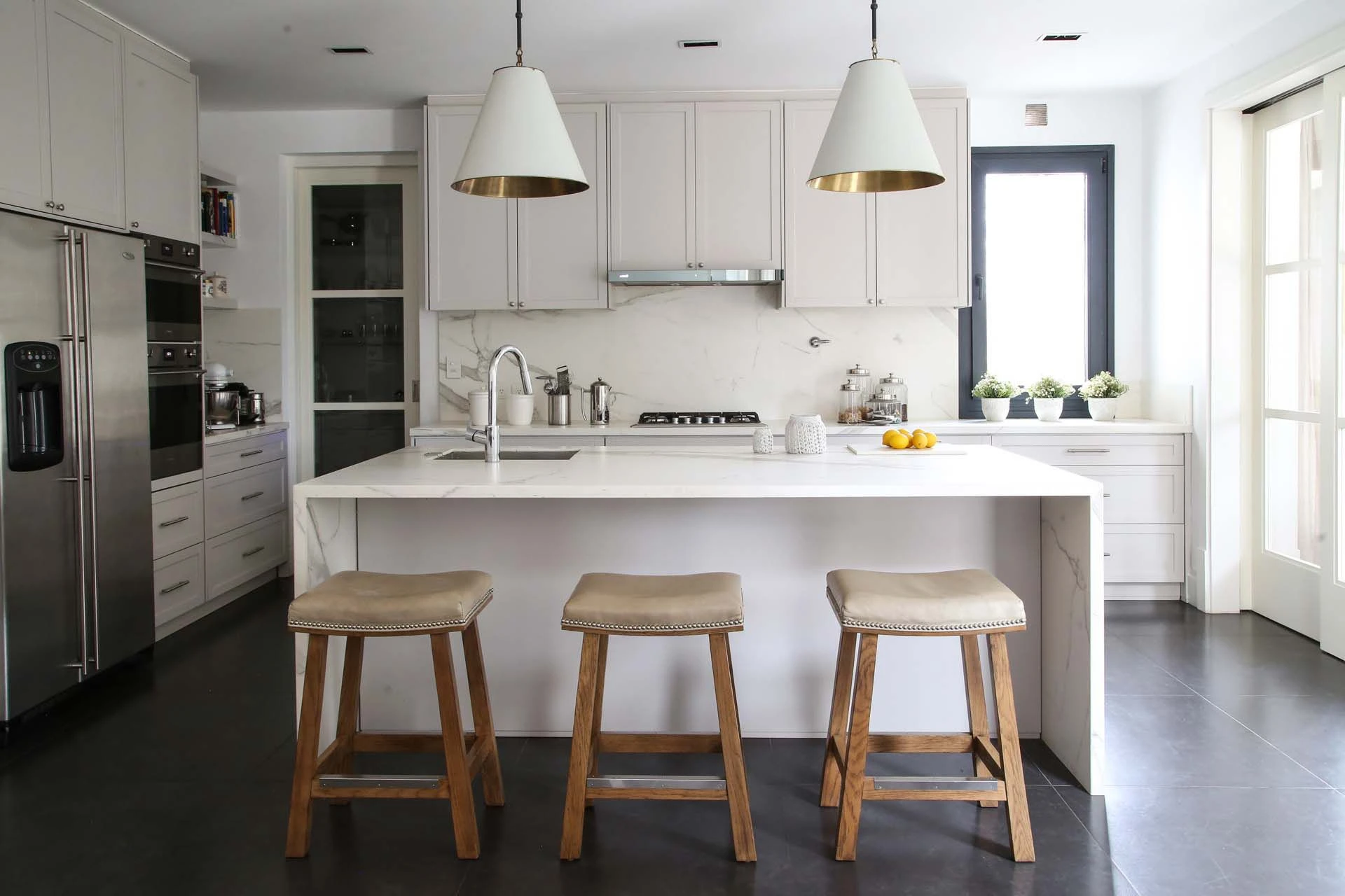 Blanco absoluto para la moderna cocina. El toque canchero lo dan las lámparas con interior dorado.