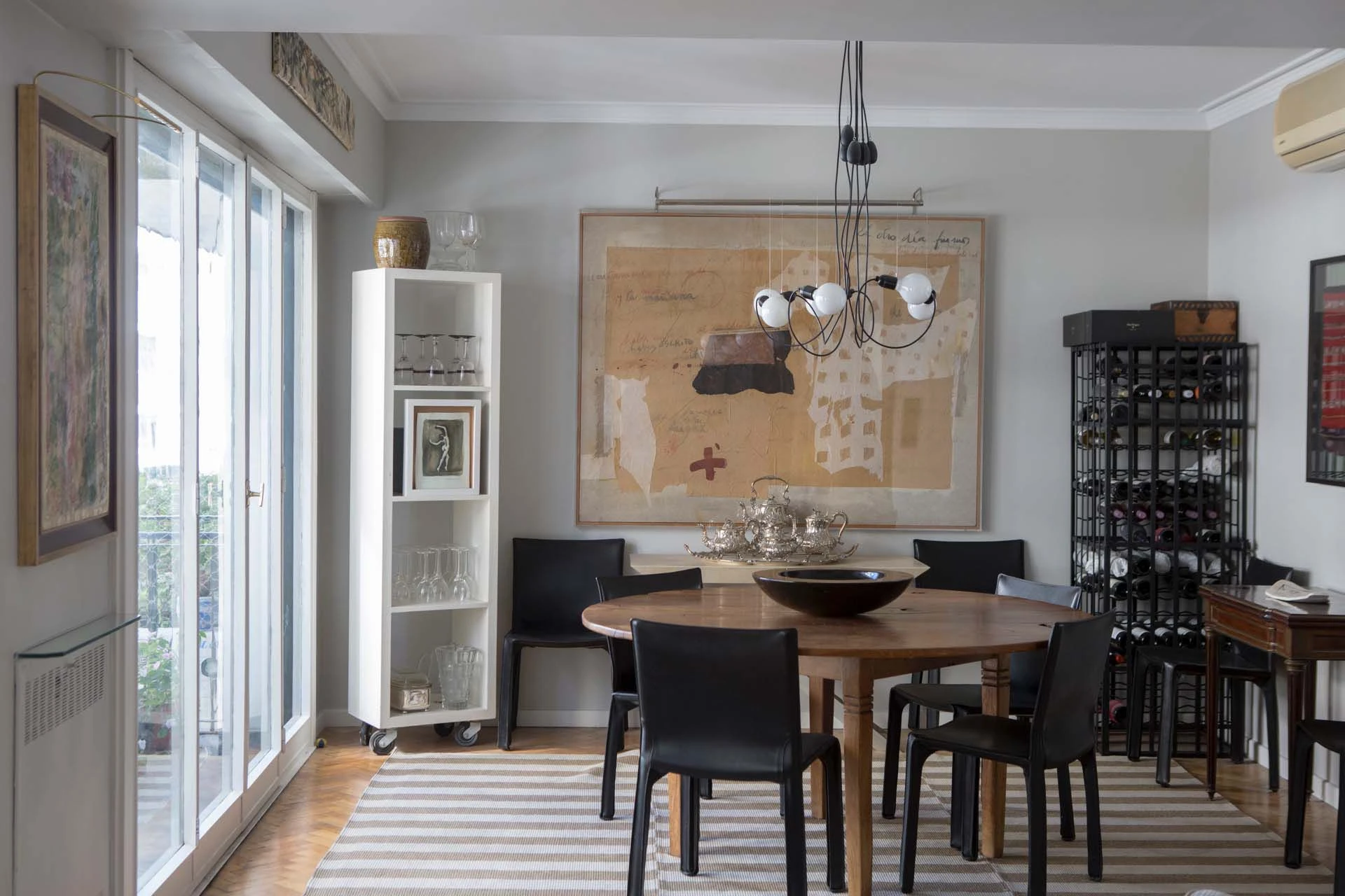 El eclecticismo del cliente se refleja también en el comedor, donde conviven sillas de diseño moderno, con una mesa rústica, arte informalista y platería europea.