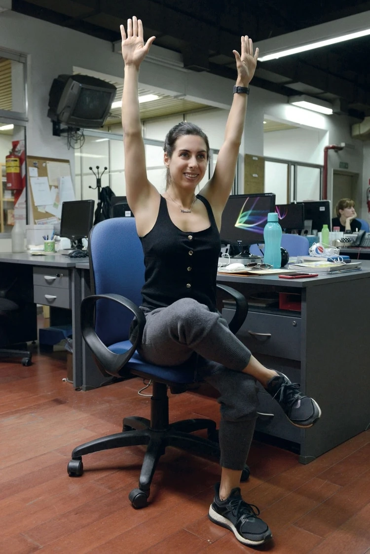 1. Sentada, cruzá la pierna derecha sobre el muslo izquierdo, estirá los brazos hacia arriba, sostené y estirá la espalda.