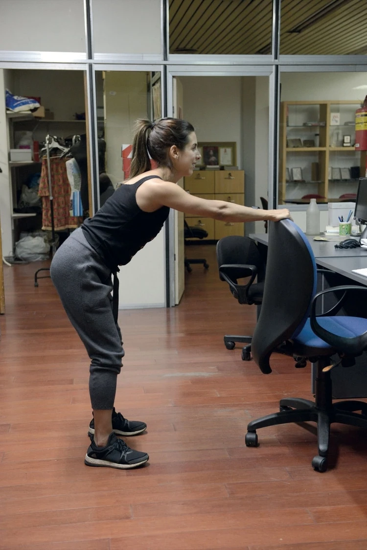 2. Separá las piernas a la altura de las caderas, flexioná las rodillas e incliná el tronco hacia adelante hasta que quede paralelo al piso.