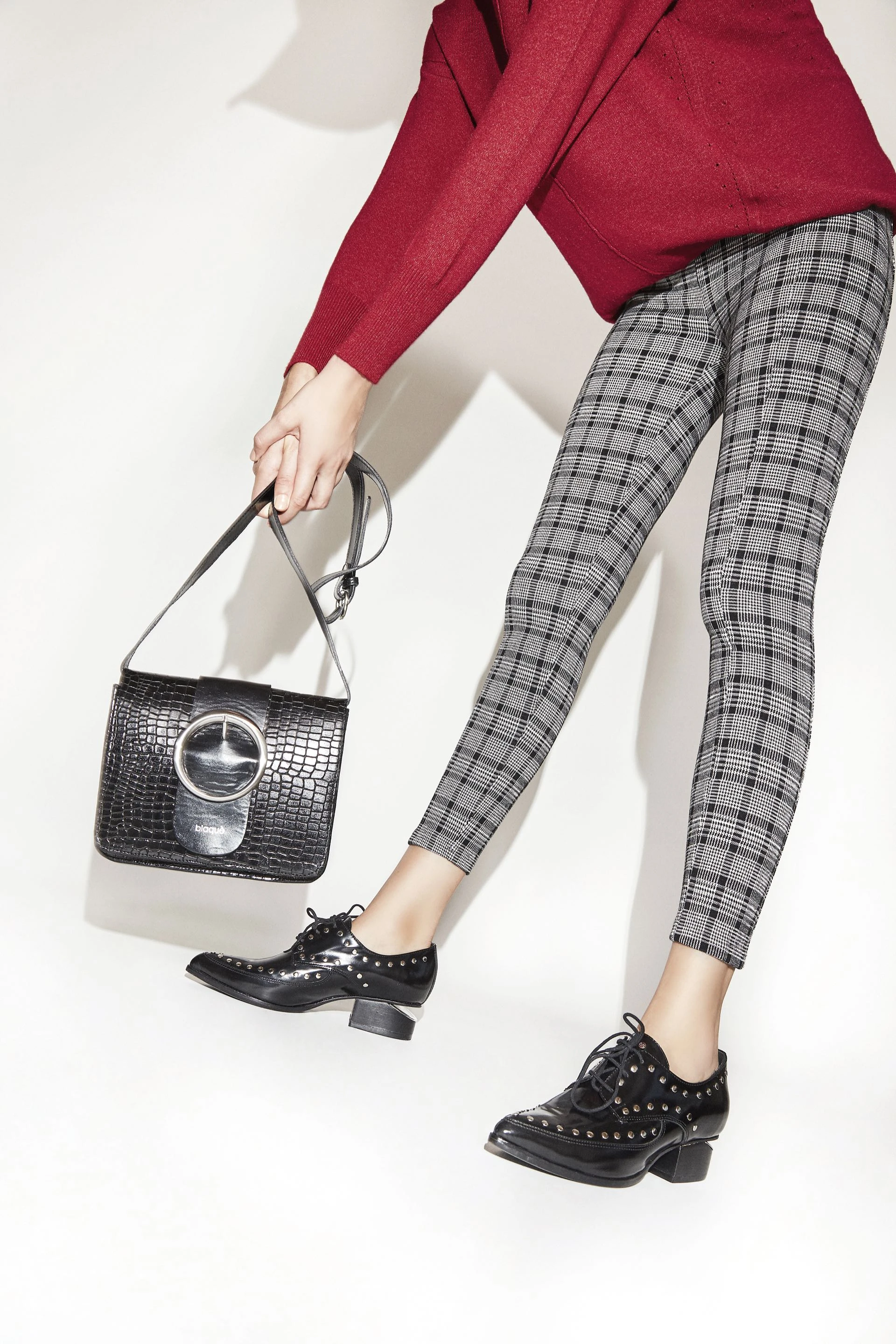 Pisada masculina. Acordonados con tachas y bandolera de cuero grabado ($ 4.100 y $ 2.390, Blaquè), calza escocesa Príncipe de Gales ($ 2.999, Basement) y suéter (Mishka).