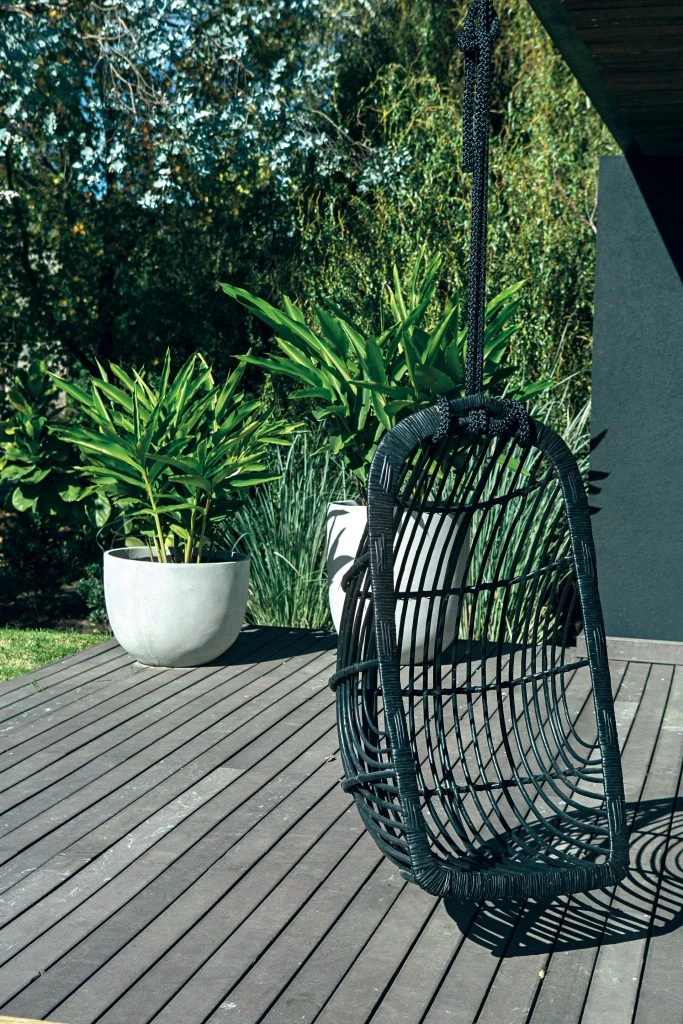 En un rincón del quincho, un sillón hamaca negro de mimbre (Design Lovers).