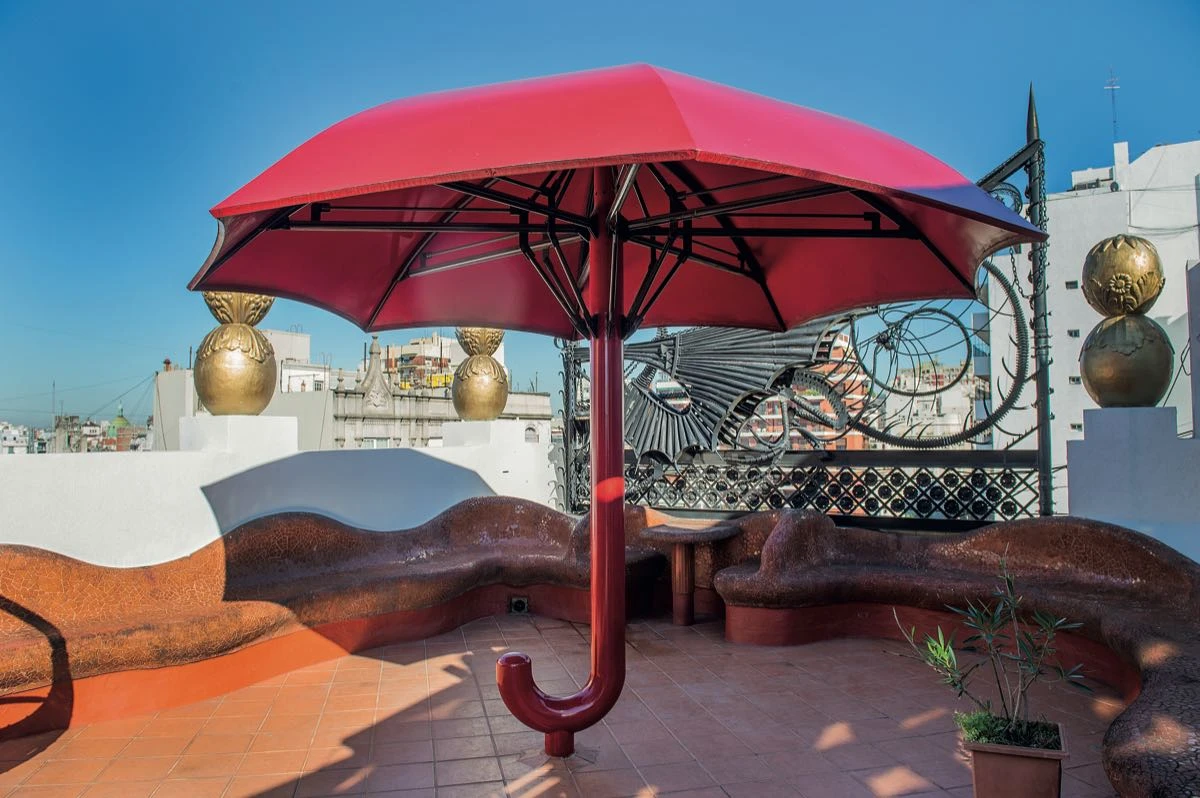 Un paraguas metálico y rojo rompe con el estilo de la terraza y genera una atracción focal disruptiva. 