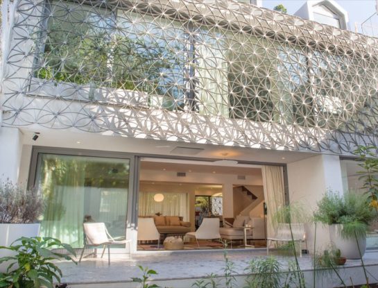 Una malla metálica de diseño escultórico tapiza las fachadas de esta casa