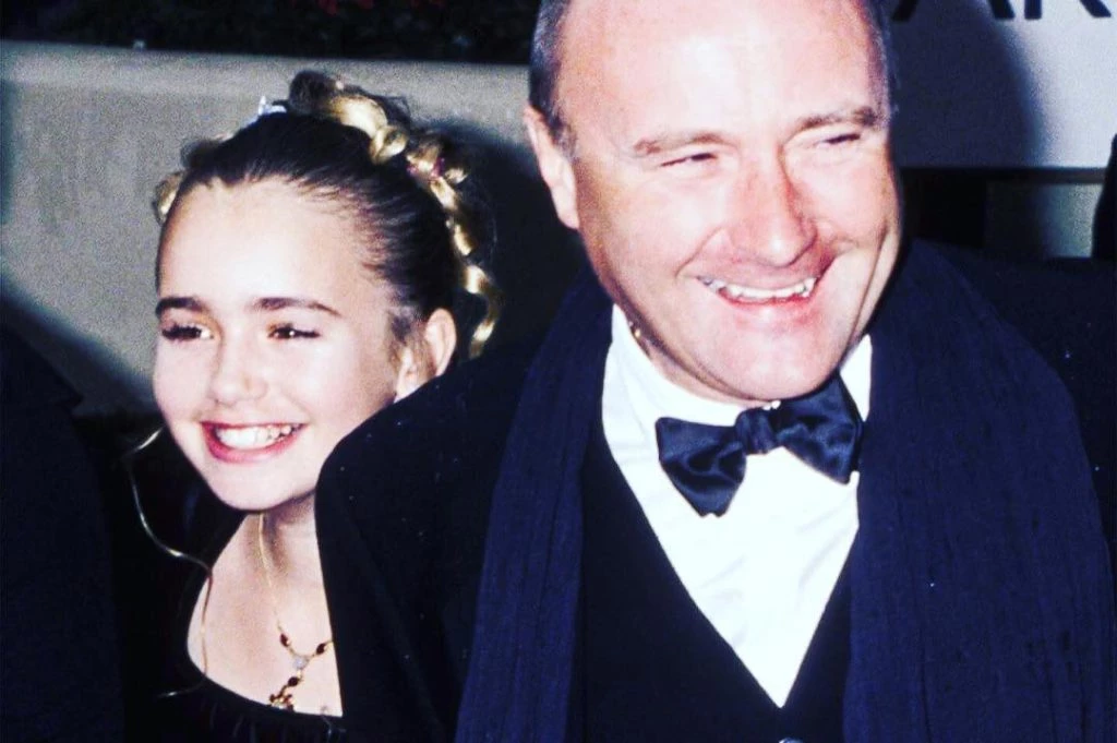 Phil Collins junto a su pequeña hija, Lily collins, sonrientes.