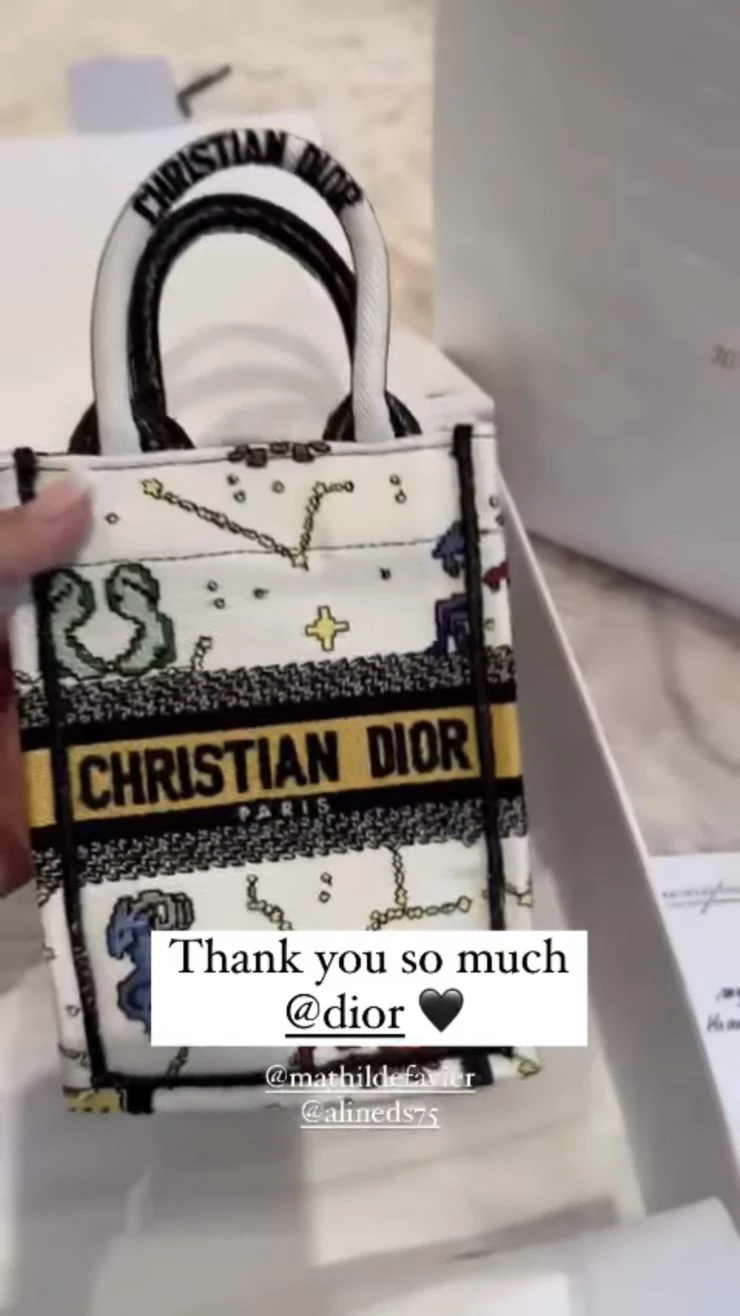 Antonela mostrando el mini bolso que recibió de regalo junto a la invitación del desfile. Foto: Instagram.