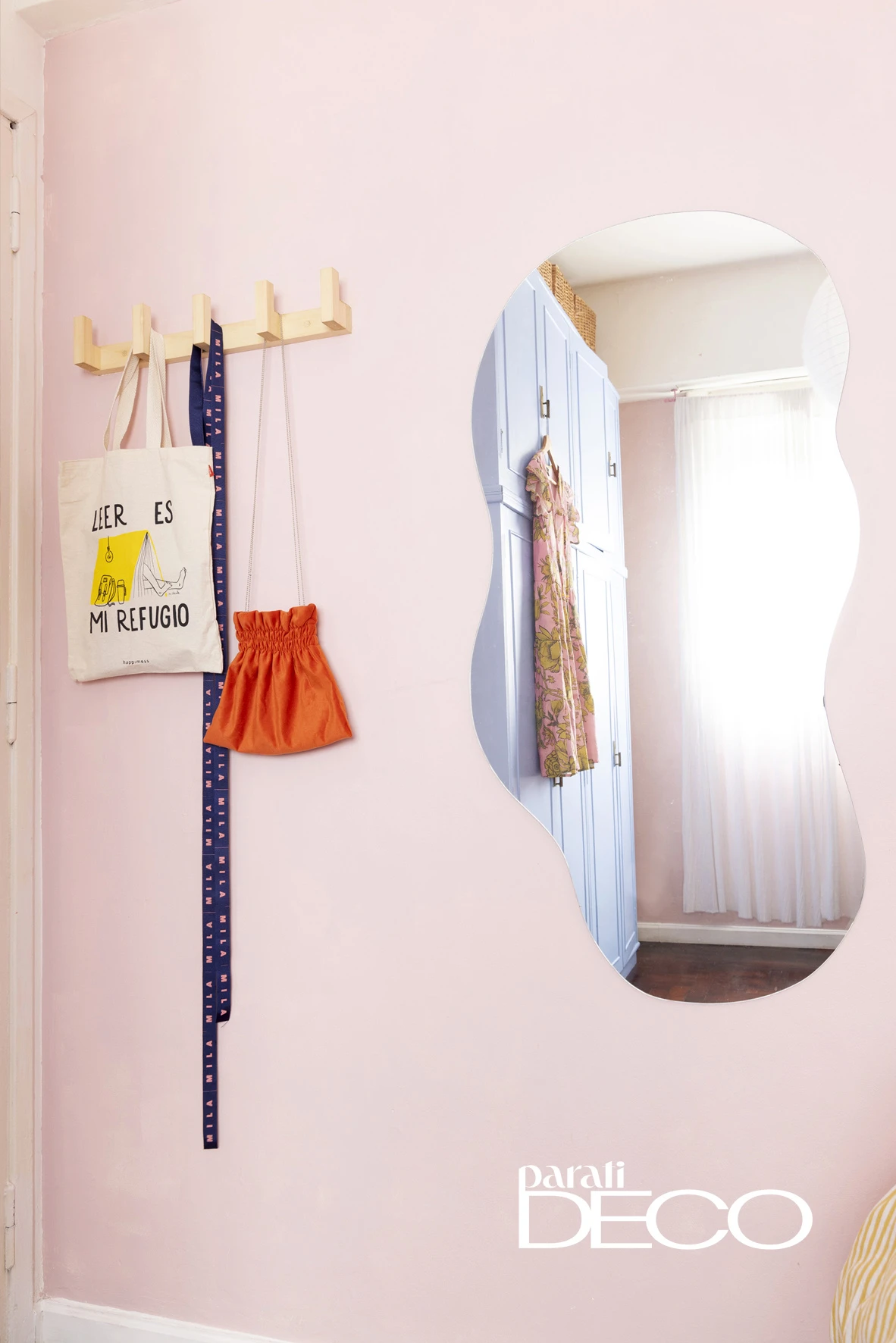 El espejo de bordes irregulares refleja la luz de un cuarto diseñado para usar y disfrutar.