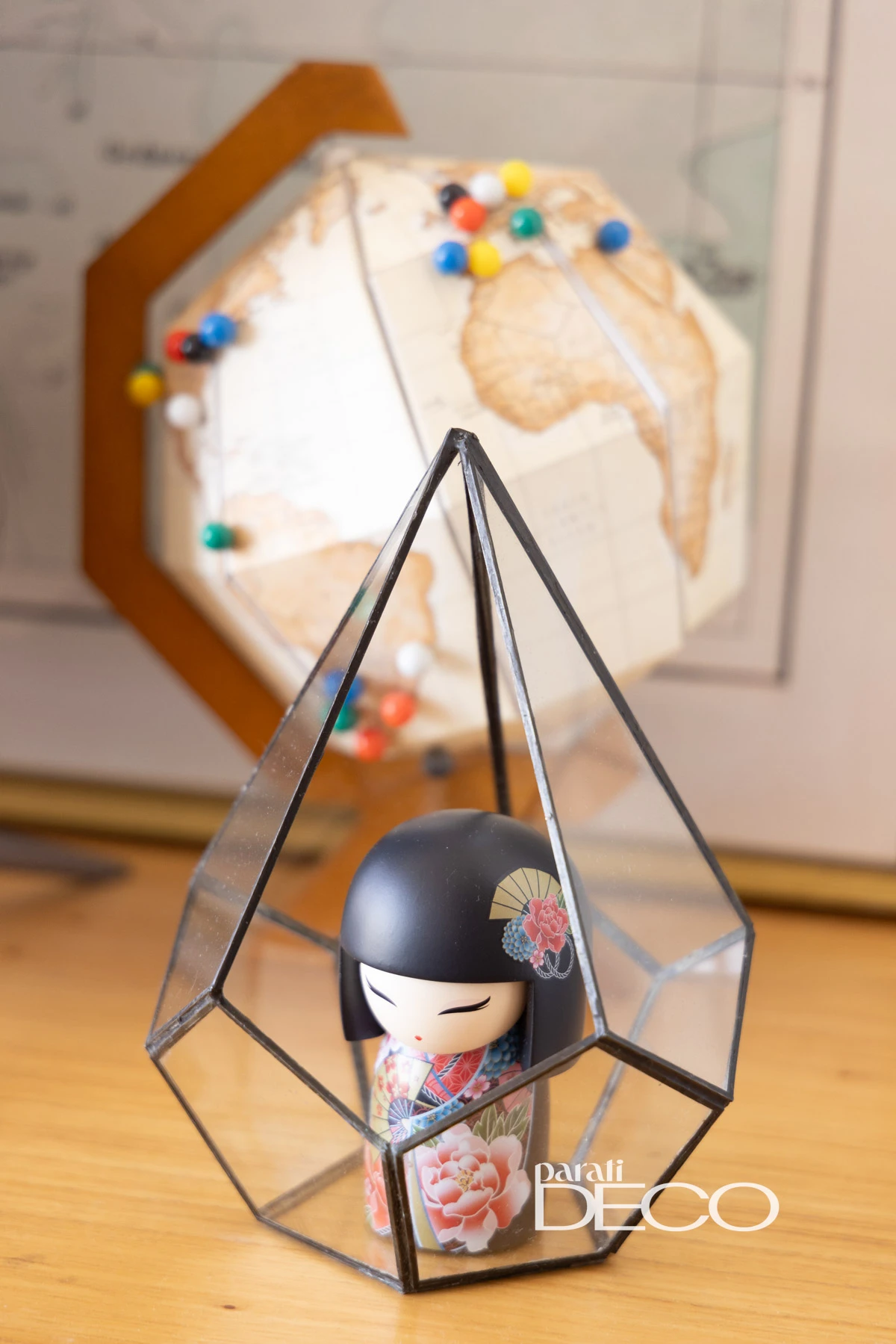 Una muñeca kokeshi y un mapamundi armado en papel plegado, como un origami. 