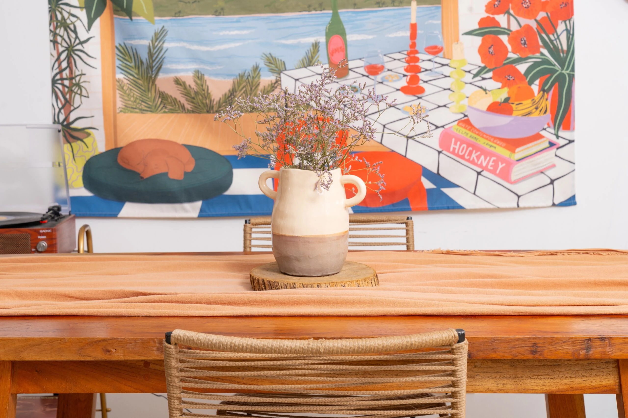 En primer plano, la pieza de cerámica hecha por Laura parece salirse del tapiz.