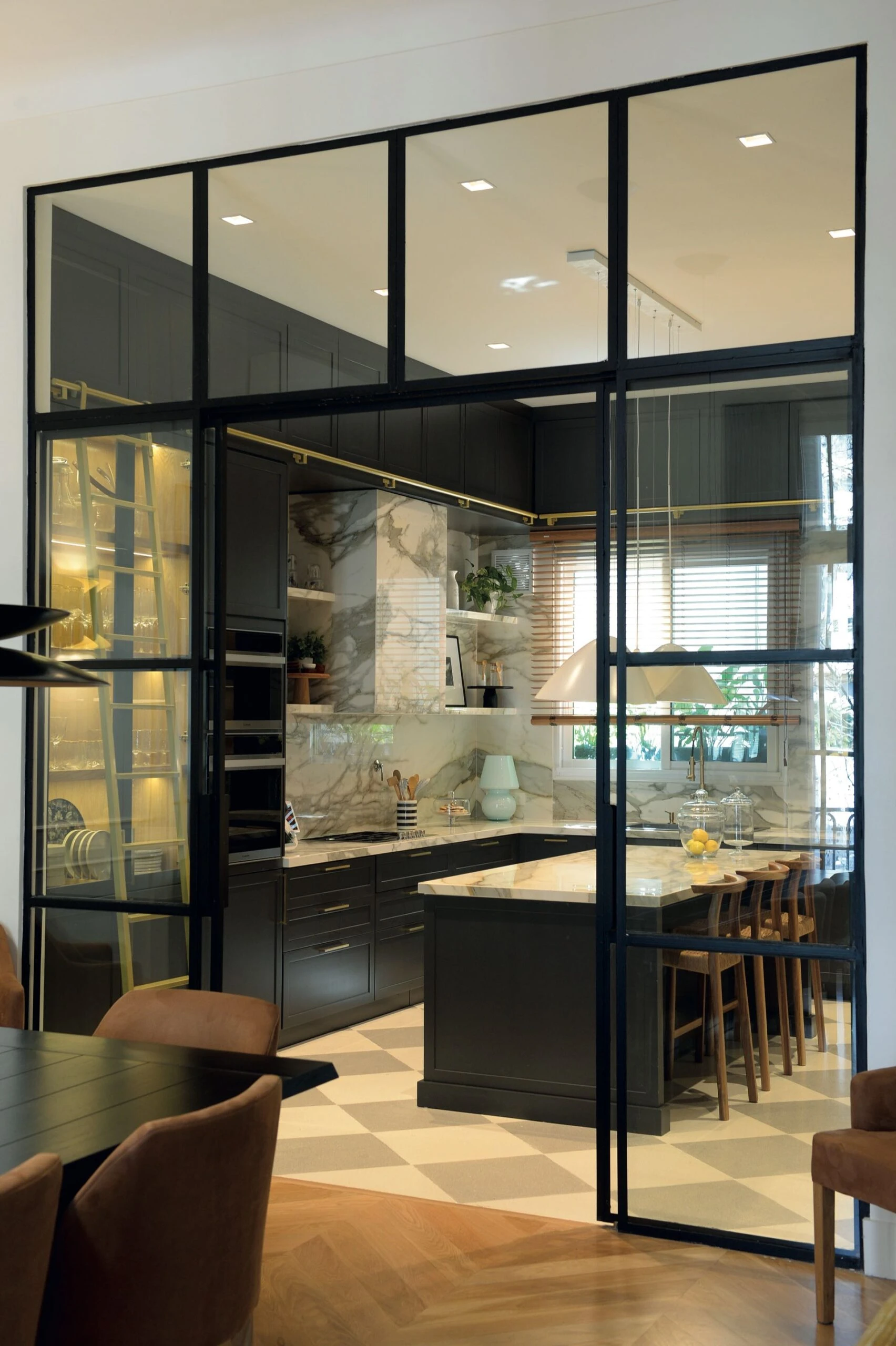 El comedor visualmente integrado a la cocina a través de un cerramiento de hierro y vidrio.