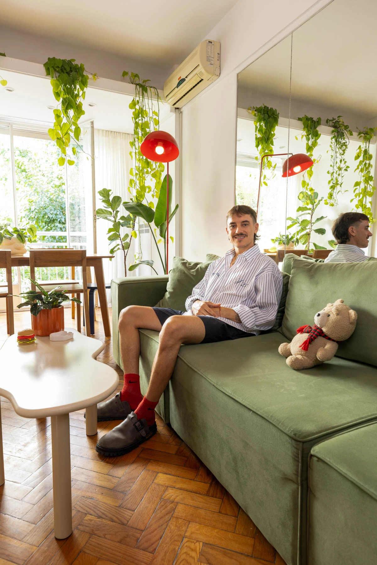 Una mesa baja, el sillón verde -estrella del living- recostado sobre un inmenso espejo que duplica el espacio. 