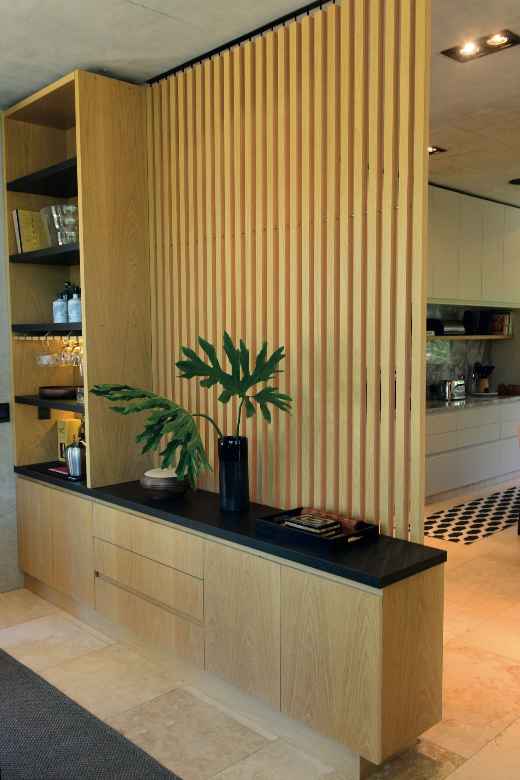 3.Un panel divisorio. El estudio Berna realizó un mueble con panel divisorio varillado de madera de roble americano que separa visualmente el living de la cocina y el espacio común. Y suma un bar con tapa de granito leather. 