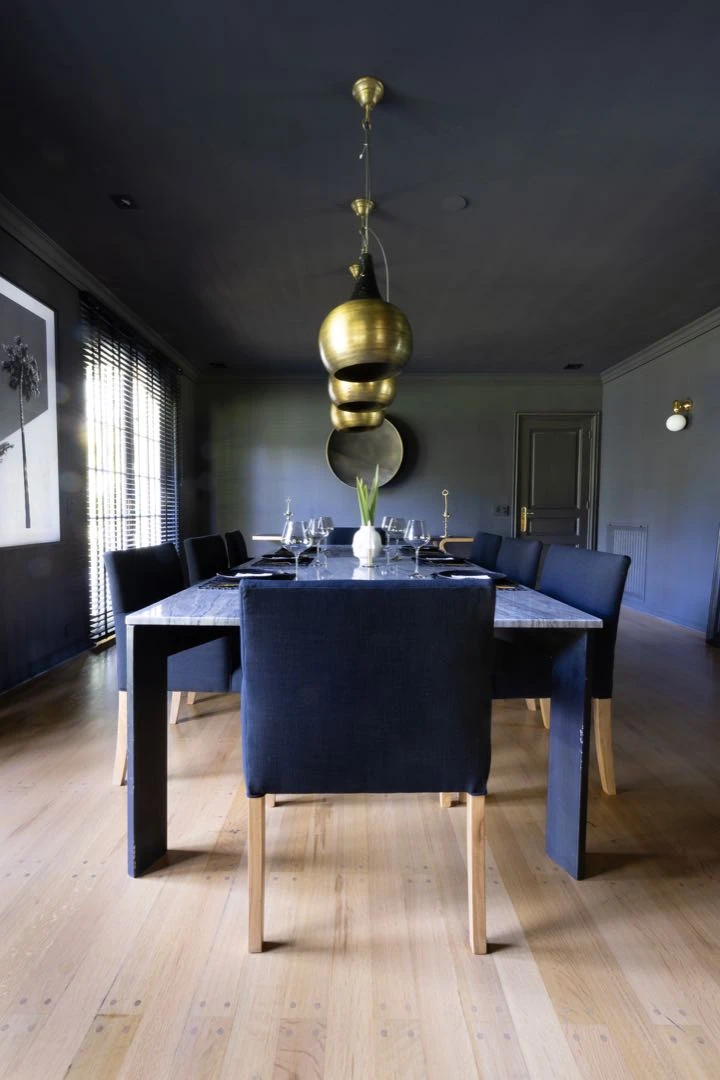 El sofisticado comedor, con textiles oscuros y lámparas doradas.