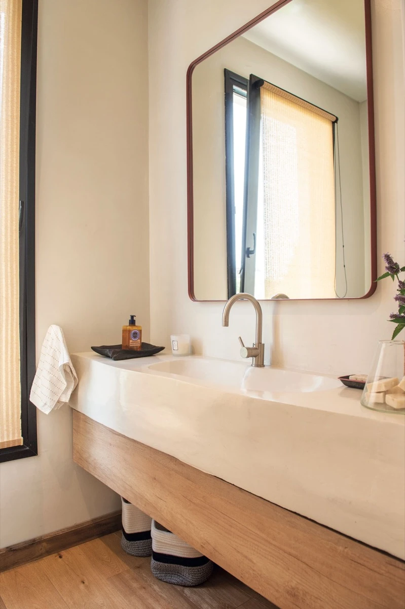 El pequeño toilette continúa con la presencia de la madera. El espejo con marco rojo es de Somos Frontera).  