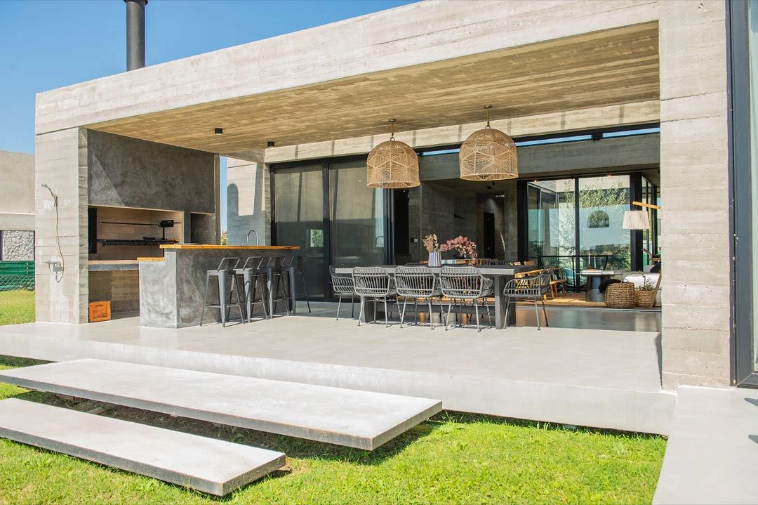 La galería con vista a la laguna incluye el sector parrilla con barra y mesa de comedor exterior. 