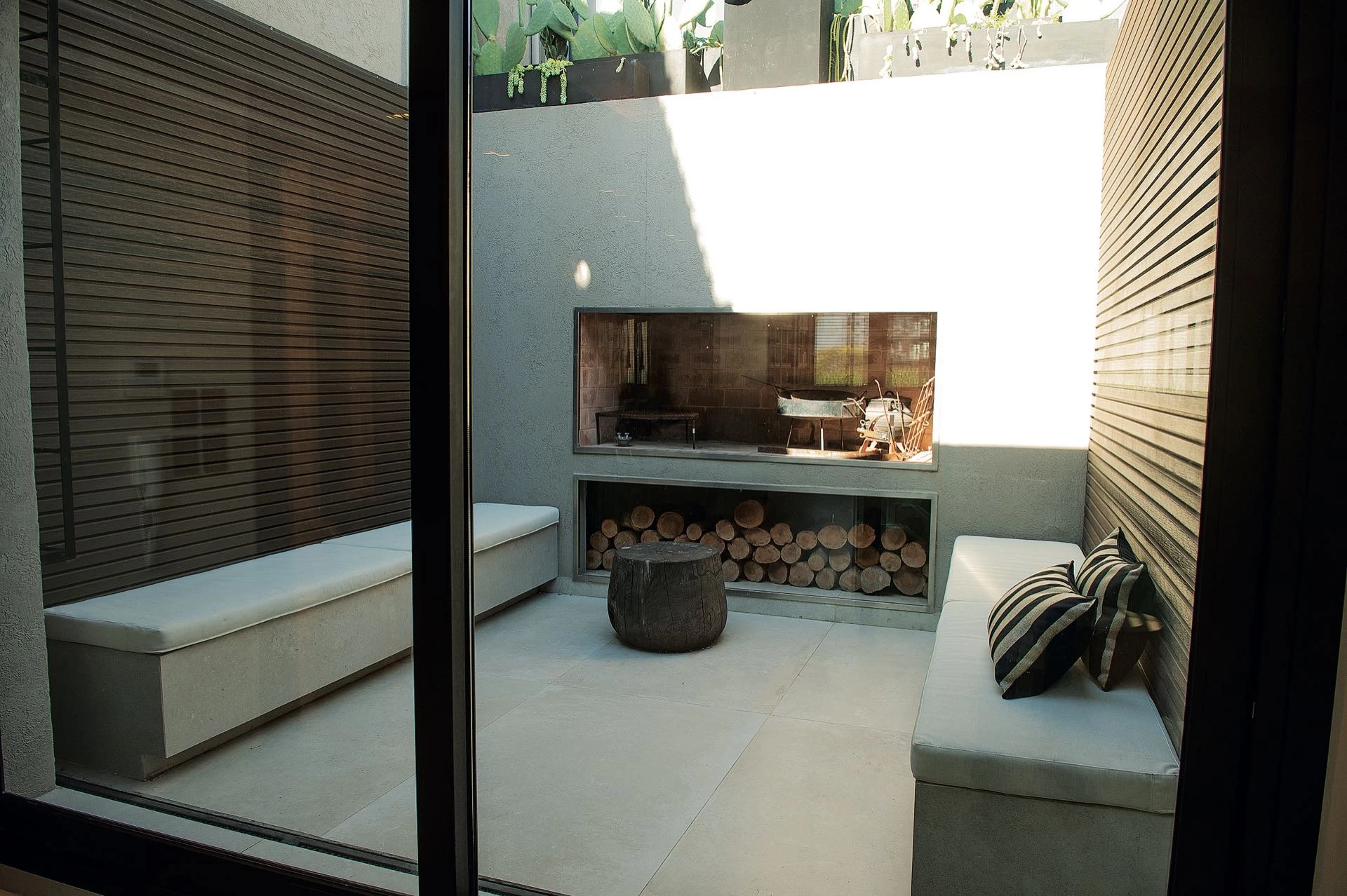 Una imagen de la terraza al aire libre, con su gran parrilla con troncos naturales.