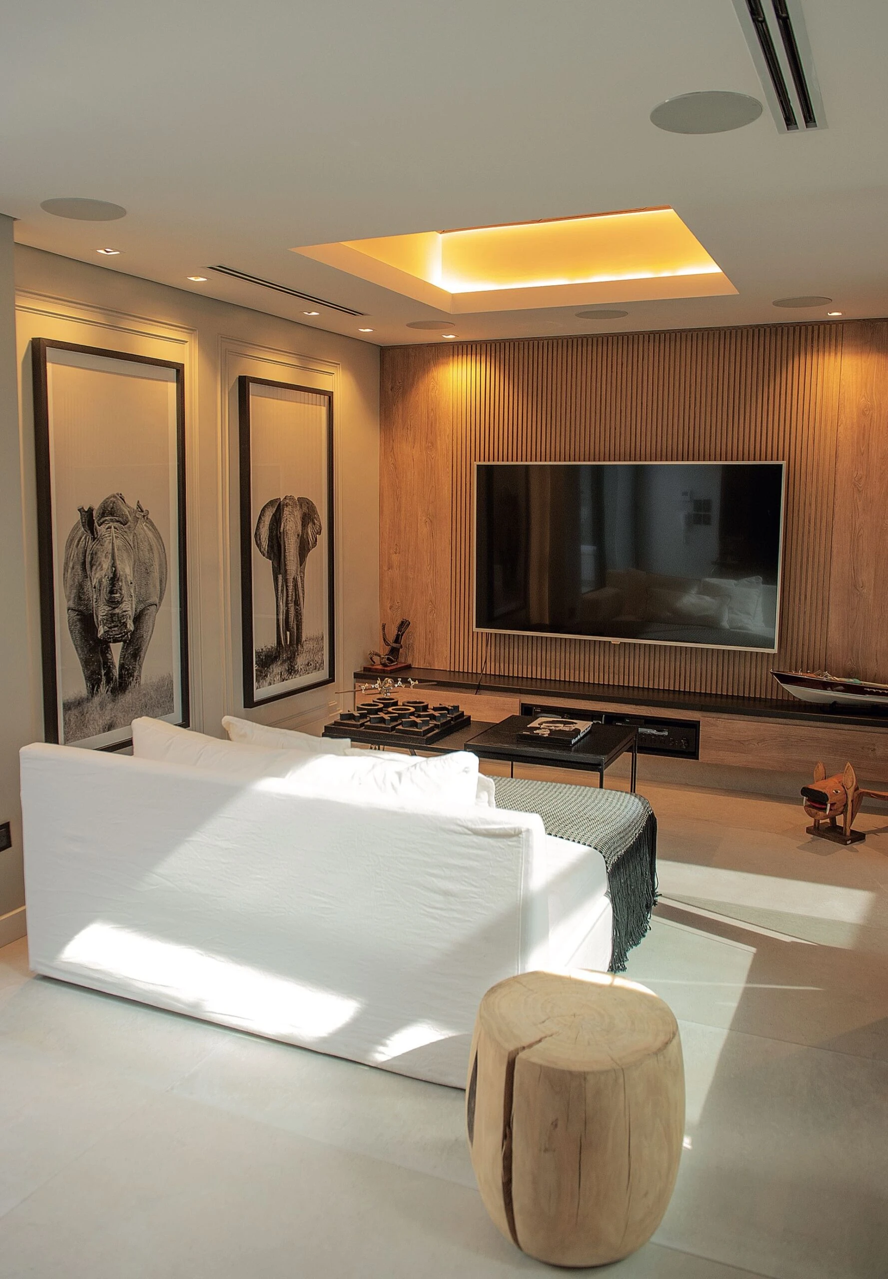 Dos grandes cuadros de animales se miran hacia un living íntimo con mesas bajas, sillón y banco de madera.