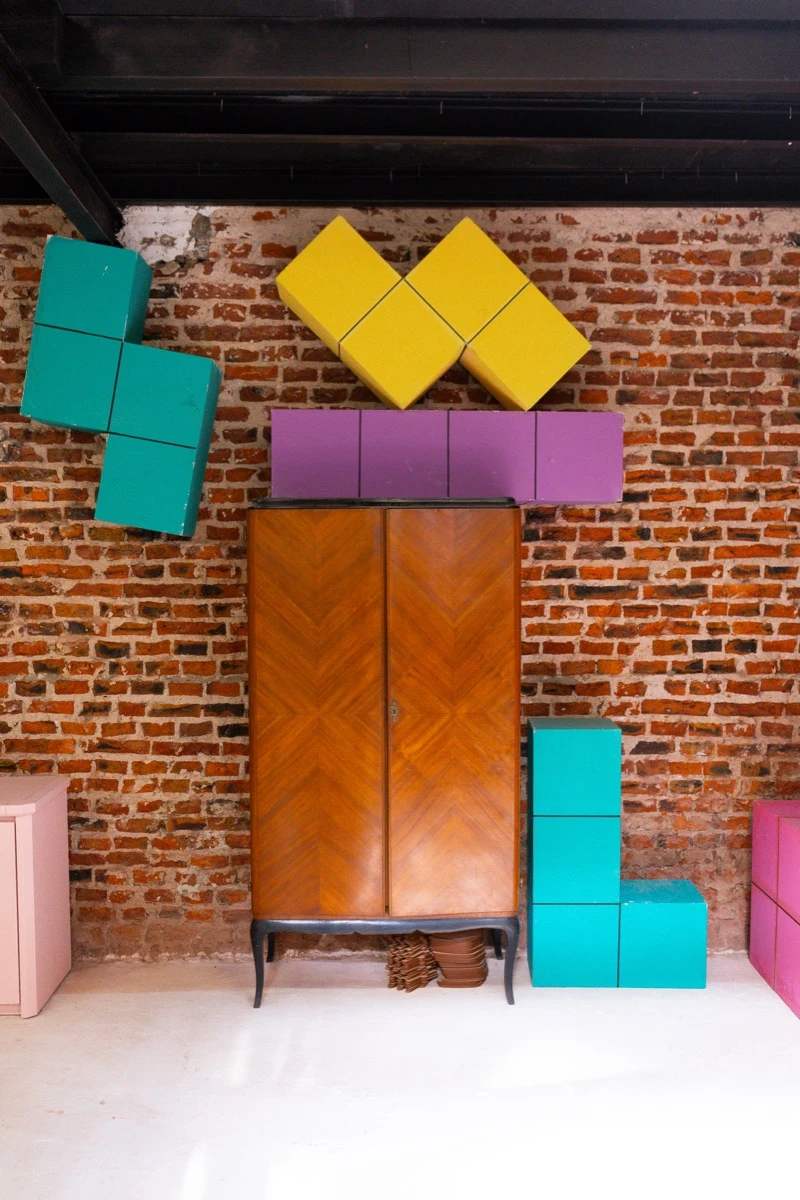 Bloques de Tetris súper pop y fuera de escala caen sobre un viejo placard: 100 % Melanie Anton Def. 