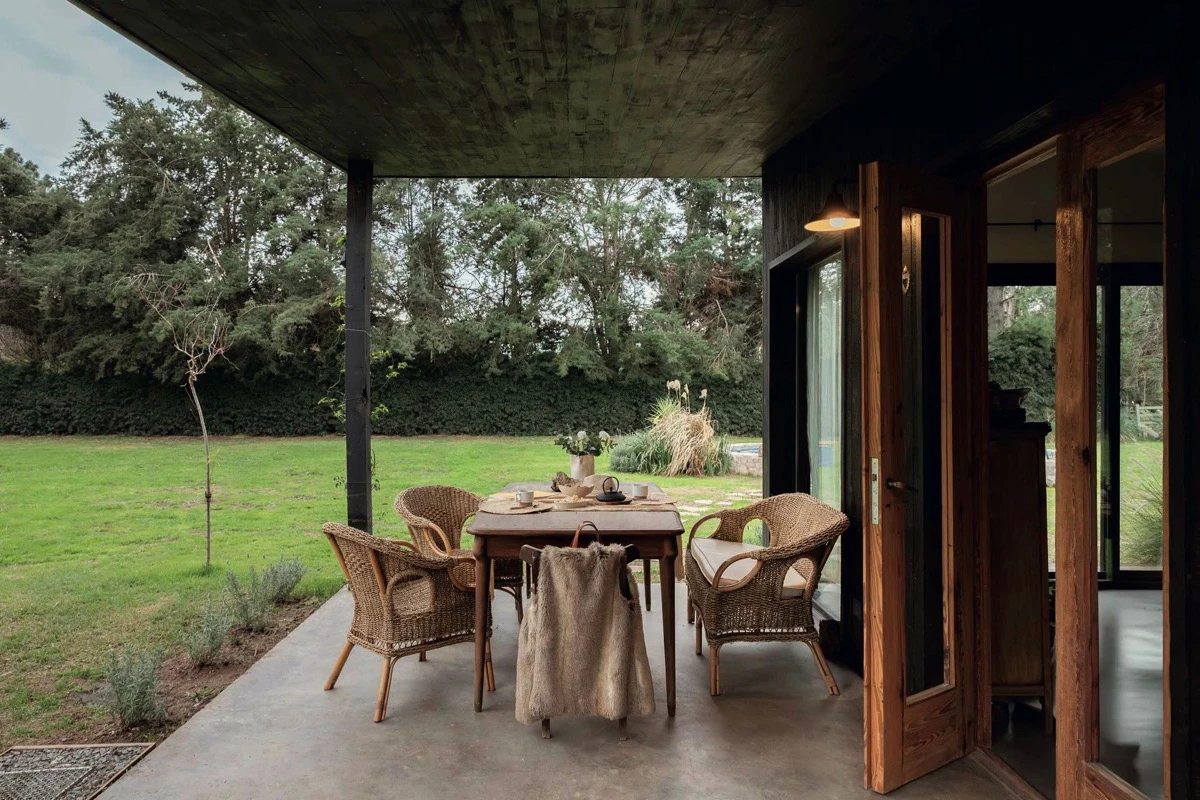 En la galería un juego de sillones de rattan acompañan a la mesa. 