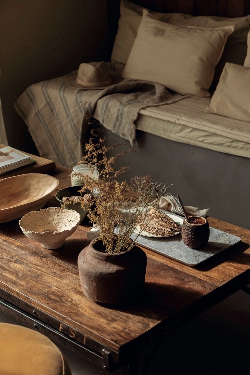 Sobre la mesa ratona, cerámica y objetos de decoración, mate, matera, cartera, cuenco de madera y mandeja de mármol tundra.  