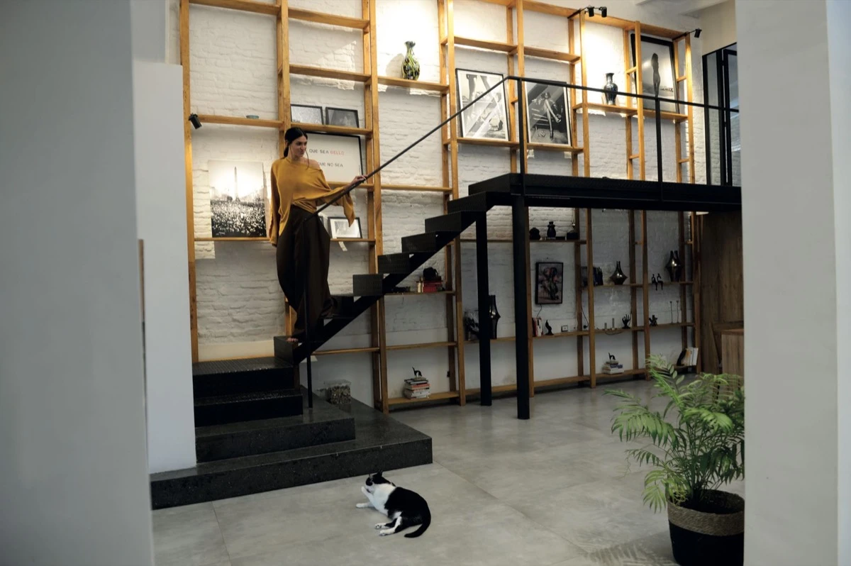 Una gran estantería de madera de petiribí y hierro recubre la pared de ladrillos pintados de blanco. 