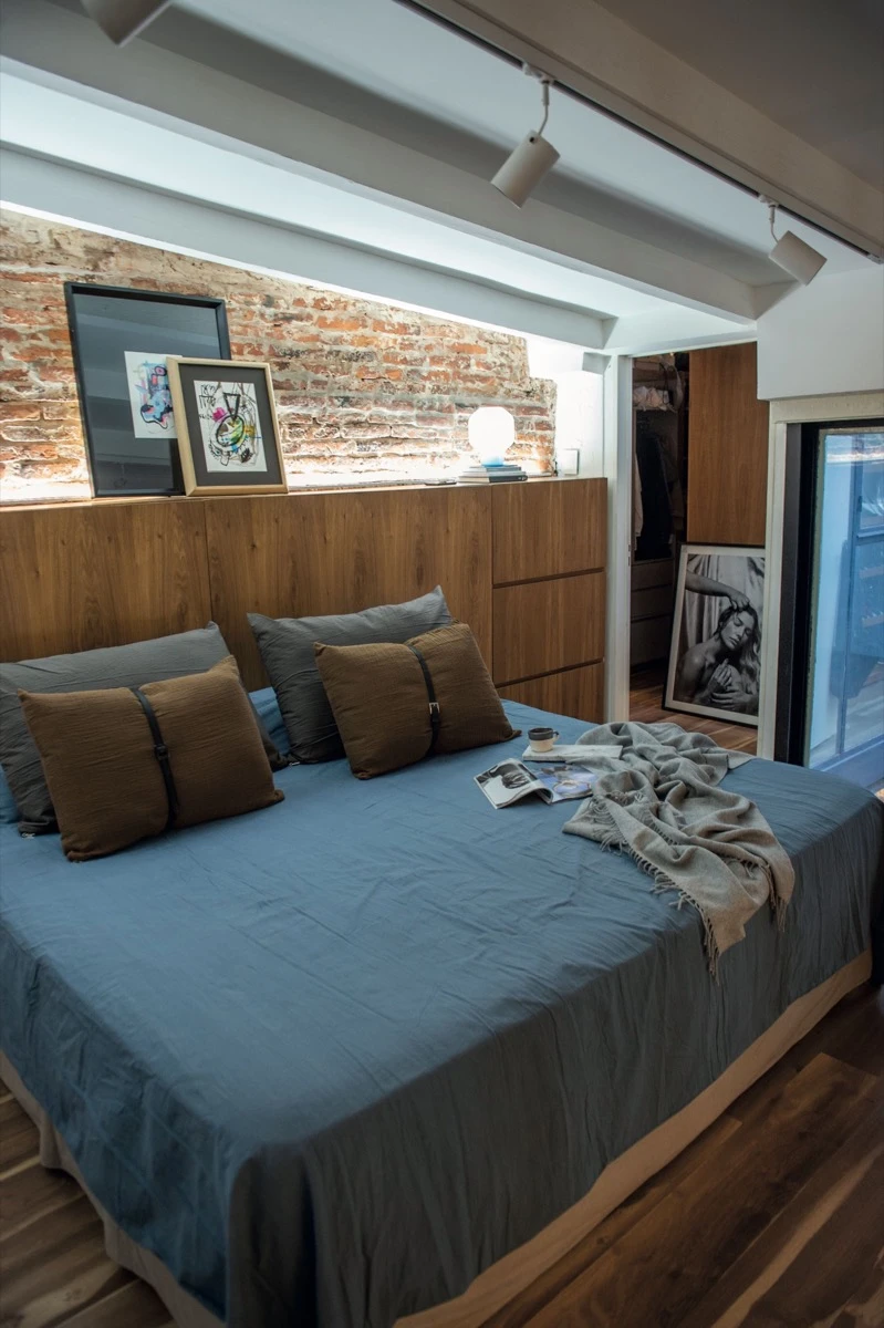 La ropa de cama, en tonos grisáceos, contrasta con los almohadones tierra 