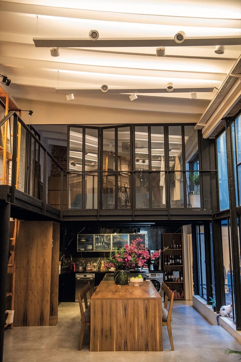 En la cocina, una imponente mesa de madera maciza -con un arreglo floral (@manojo.manojo) y una frutera (@castrocorbar)- actúa como corazón del loft.  