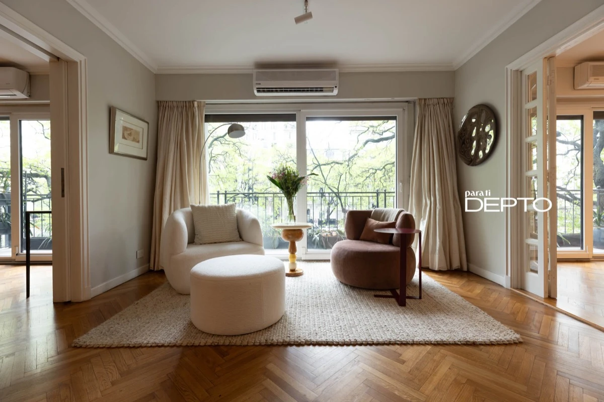 Un pequeño living junto al ventanal con vista a los árboles de Palermo. 