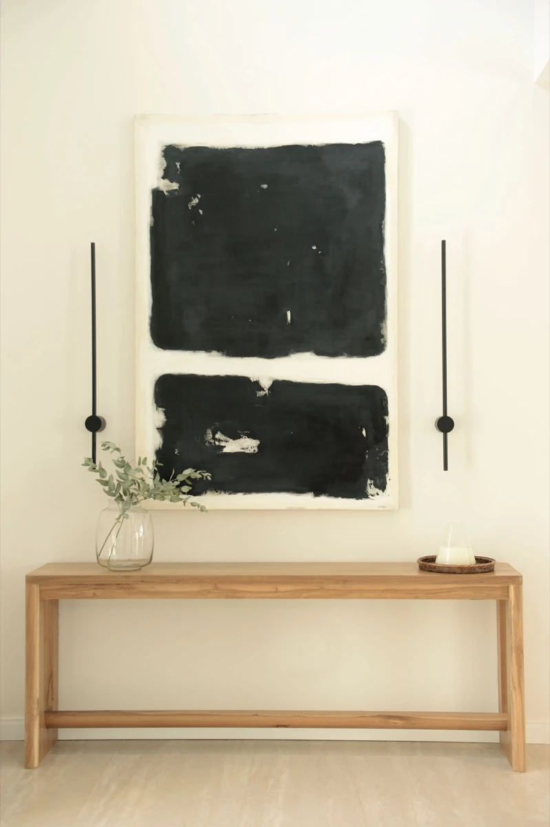 En el hall de entrada, una consola de madera dialoga con un cuadro de Paula Gilly.