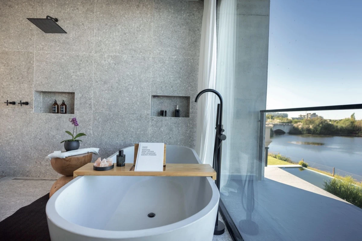 La bañera refleja el cielo y los accesorios complementan la escena de bienestar.