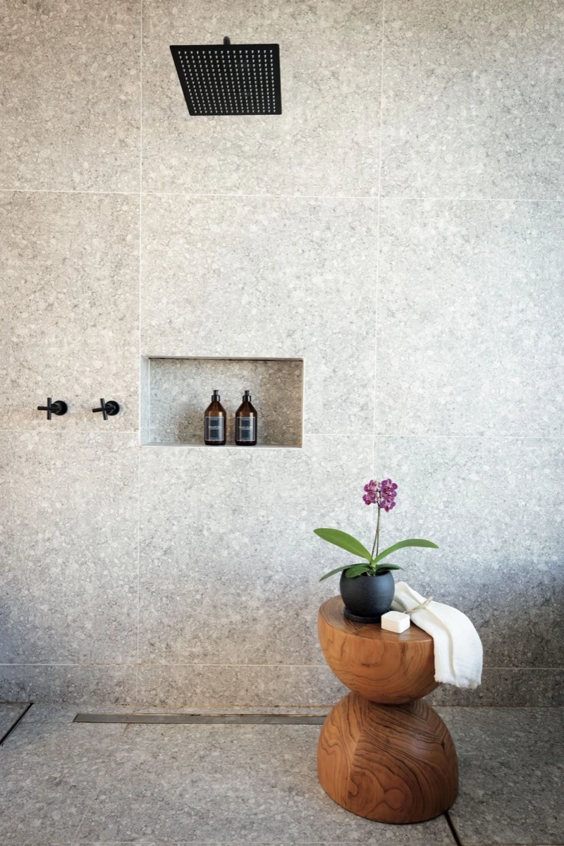 Sobre el banco de madera, una orquídea en maceta redonda y una toalla de mano.