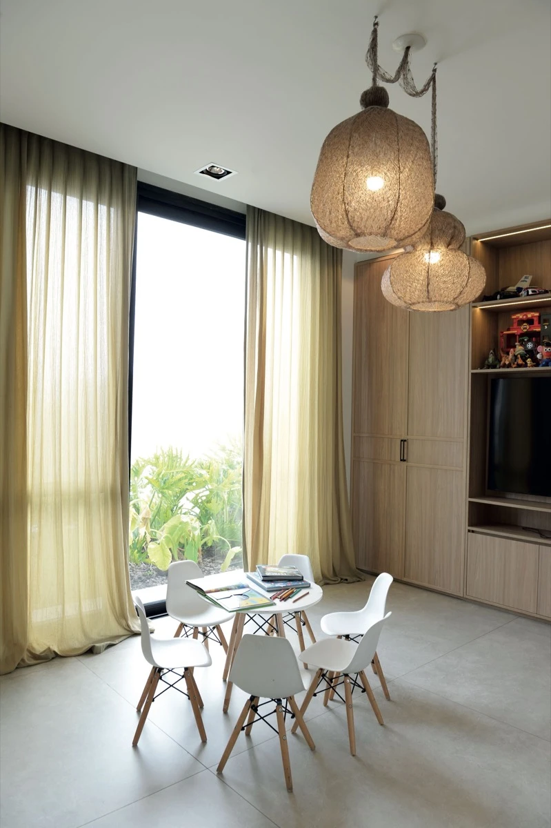 El playroom, con mini mesa y lámparas colgantes Farola (La Feliz), más cortinas en suave tono verde.