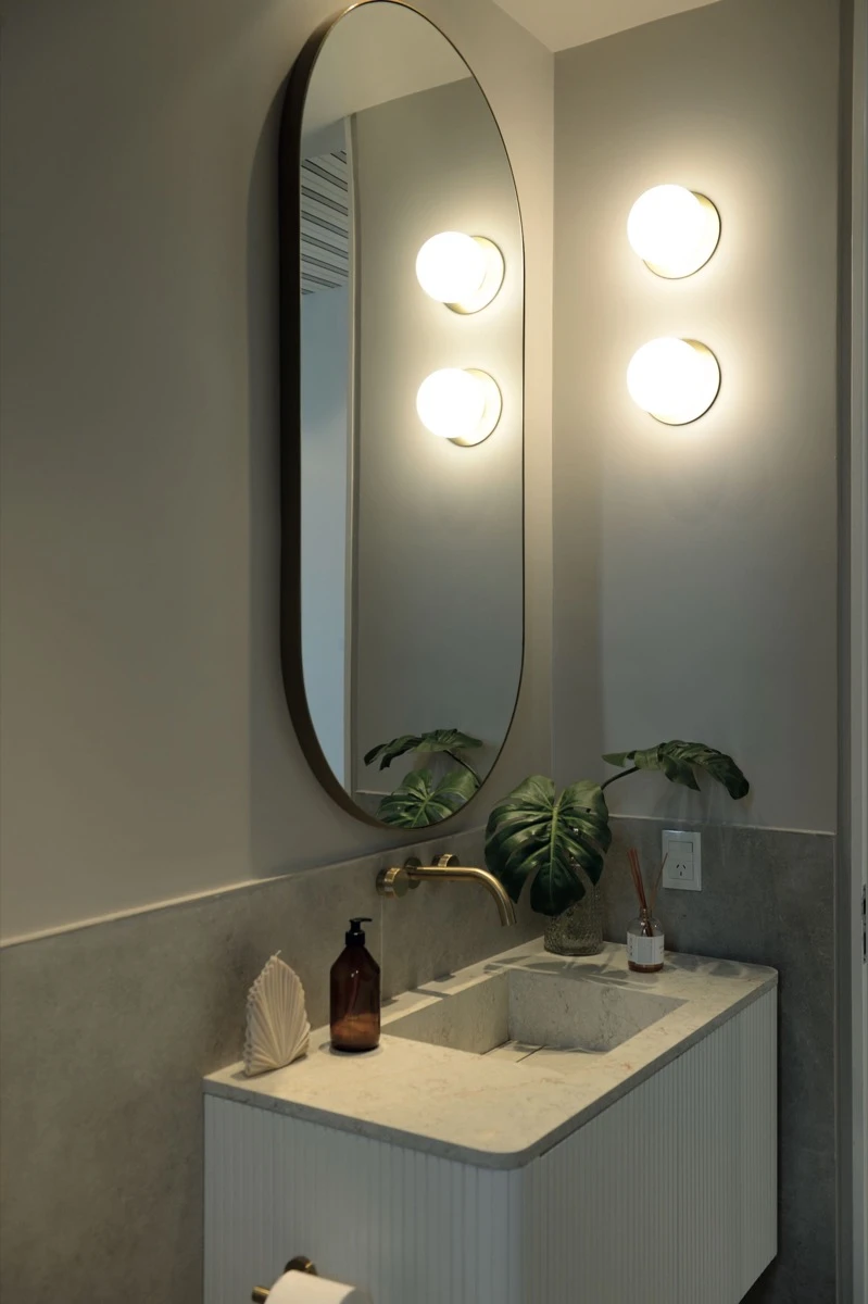 El vanitory flotante de mármol Calacatta con luz, grifería y espejo irregular.