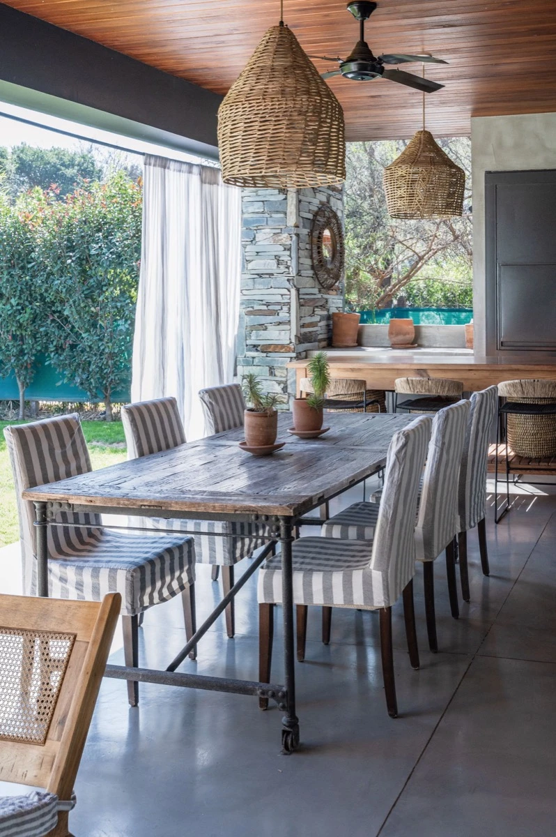 En la gran mesa de comedor exterior, las sillas van tapizadas en lino de rayas grises y blancas. 
