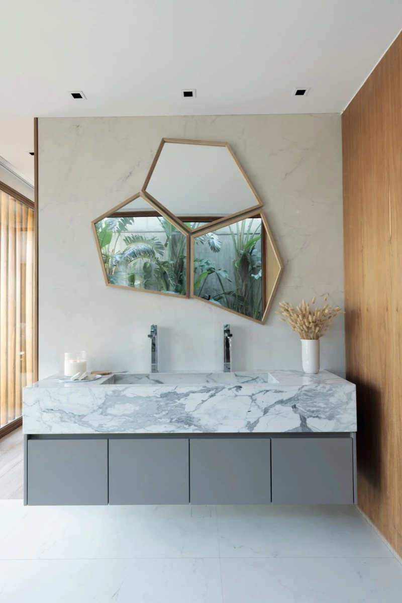 El verde exterior se replica en el espejo tríptico de formas irregulares