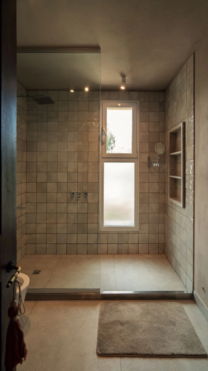 Con paredes revestidas en tocetos artesanales Gouache Brume, de 15 x 15 cm (SBG) y solados en placas de Liscio Ivory Out, de 80 x 80 cm, 