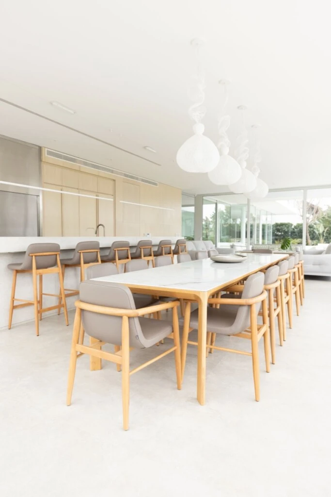 En el comedor del quincho, la mesa con cubierta de Neolith y estructura de madera dialoga en armonía con las sillas de madera de líneas suaves y proporciones generosas 