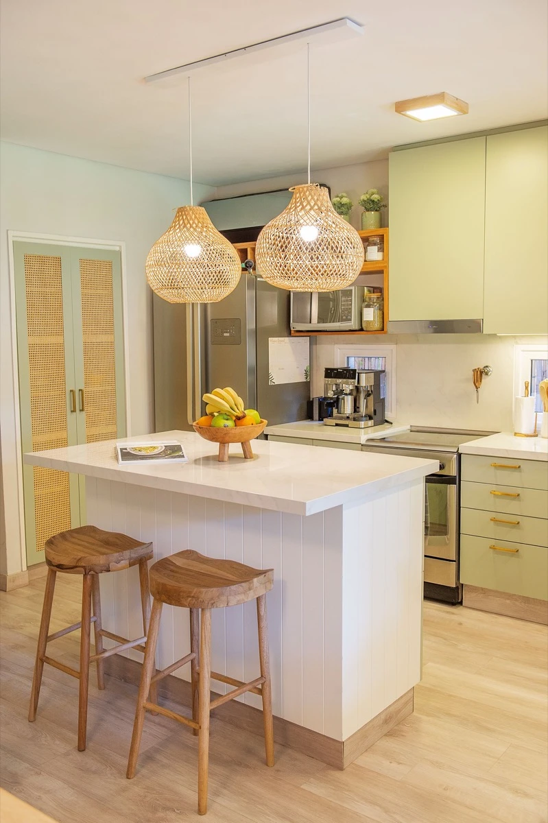 Sobre la isla, una frutera de madera y una estantería abierta para el microondas junto al spot de café. 