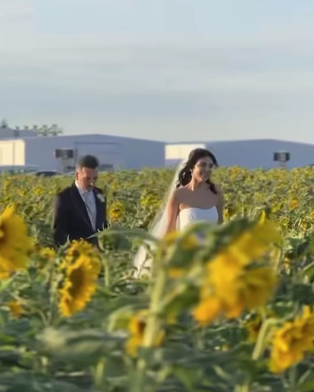 La escena inicial del video parece un fotograma de película: un campo infinito de girasoles abiertos en plena floración y un corredor natural entre las plantas, armado como pasillo de ceremonia. Sobre ese sendero amarillo y luminoso, la pareja camina hacia un altar sencillo, integrado al paisaje y pensado para que la naturaleza domine la imagen.

La luz del atardecer realza todo: el dorado del campo, el movimiento suave de las flores y la intimidad del momento. No hay estructuras pesadas ni elementos que compitan con el entorno. La apuesta es clara: dejar que la naturaleza sea el decorado.

Este tipo de ceremonias inmersivas, donde el escenario natural se convierte en parte del ritual, gana cada vez más terreno entre parejas que buscan autenticidad, emoción y simplicidad estética. El campo de girasoles aporta, además, un simbolismo potente: vitalidad, alegría y una idea muy poética de “buscar la luz”.

Una fiesta bajo techo vidriado: el jardín de invierno que dejó a todos sin palabras

Tras la ceremonia, el video muestra un segundo escenario igual de impactante: un jardín de invierno gigante, montado especialmente para la fiesta. Se trata de una estructura completamente vidriada, con paredes y techo transparentes que permiten ver el cielo nocturno desde adentro.

La iluminación cálida, a base de microleds y guirnaldas, crea un clima íntimo y elegante. Las mesas -tanto largas como redondas- están decoradas con flores blancas y verdes, velas y vajilla neutra. Todo pensado en clave natural, sin recargar, manteniendo la armonía con lo que ocurrió horas antes en el campo.

La gran virtud del espacio es que combina protección y aire libre: desde adentro se ve el cielo estrellado como si no hubiera techo, pero con la comodidad y el resguardo de un salón diseñado para una noche especial. El efecto es cinematográfico.

El cielo como protagonista y un cierre con fuegos artificiales

En los tramos finales del video, el techo vidriado funciona como pantalla: el cielo oscuro, las estrellas y el brillo del exterior se integran al ambiente. La fiesta transcurre literalmente “bajo las estrellas”, en un escenario que mezcla naturaleza y diseño sin perder calidez.

El cierre llega con fuegos artificiales en tonos dorados y blancos, ubicados a una distancia segura del salón. Reflejan su luz sobre los paneles del techo y generan un efecto envolvente, delicado y festivo. Es un final que potencia el clima emocional de toda la celebración.

Por qué estas bodas inspiran tanto

Las bodas como esta combinan tres elementos que conectan con una búsqueda contemporánea:

Rituales auténticos, donde los protagonistas se sienten parte del paisaje.

Experiencias sensoriales, donde la luz, el entorno y la atmósfera importan tanto como la decoración.

Naturaleza + diseño, en equilibrio, sin exageraciones y con intención clara.

La boda chaqueña ya circula por redes como ejemplo de una tendencia que crece: celebrar en escenarios que cuentan una historia, sin necesidad de grandes producciones, sino priorizando el entorno, la identidad de la pareja y la magia del momento.