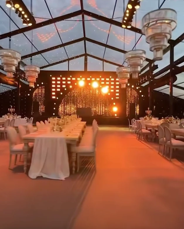 La escena inicial del video parece un fotograma de película: un campo infinito de girasoles abiertos en plena floración y un corredor natural entre las plantas, armado como pasillo de ceremonia. Sobre ese sendero amarillo y luminoso, la pareja camina hacia un altar sencillo, integrado al paisaje y pensado para que la naturaleza domine la imagen.

La luz del atardecer realza todo: el dorado del campo, el movimiento suave de las flores y la intimidad del momento. No hay estructuras pesadas ni elementos que compitan con el entorno. La apuesta es clara: dejar que la naturaleza sea el decorado.

Este tipo de ceremonias inmersivas, donde el escenario natural se convierte en parte del ritual, gana cada vez más terreno entre parejas que buscan autenticidad, emoción y simplicidad estética. El campo de girasoles aporta, además, un simbolismo potente: vitalidad, alegría y una idea muy poética de “buscar la luz”.

Una fiesta bajo techo vidriado: el jardín de invierno que dejó a todos sin palabras

Tras la ceremonia, el video muestra un segundo escenario igual de impactante: un jardín de invierno gigante, montado especialmente para la fiesta. Se trata de una estructura completamente vidriada, con paredes y techo transparentes que permiten ver el cielo nocturno desde adentro.

La iluminación cálida, a base de microleds y guirnaldas, crea un clima íntimo y elegante. Las mesas -tanto largas como redondas- están decoradas con flores blancas y verdes, velas y vajilla neutra. Todo pensado en clave natural, sin recargar, manteniendo la armonía con lo que ocurrió horas antes en el campo.

La gran virtud del espacio es que combina protección y aire libre: desde adentro se ve el cielo estrellado como si no hubiera techo, pero con la comodidad y el resguardo de un salón diseñado para una noche especial. El efecto es cinematográfico.

El cielo como protagonista y un cierre con fuegos artificiales

En los tramos finales del video, el techo vidriado funciona como pantalla: el cielo oscuro, las estrellas y el brillo del exterior se integran al ambiente. La fiesta transcurre literalmente “bajo las estrellas”, en un escenario que mezcla naturaleza y diseño sin perder calidez.

El cierre llega con fuegos artificiales en tonos dorados y blancos, ubicados a una distancia segura del salón. Reflejan su luz sobre los paneles del techo y generan un efecto envolvente, delicado y festivo. Es un final que potencia el clima emocional de toda la celebración.

Por qué estas bodas inspiran tanto

Las bodas como esta combinan tres elementos que conectan con una búsqueda contemporánea:

Rituales auténticos, donde los protagonistas se sienten parte del paisaje.

Experiencias sensoriales, donde la luz, el entorno y la atmósfera importan tanto como la decoración.

Naturaleza + diseño, en equilibrio, sin exageraciones y con intención clara.

La boda chaqueña ya circula por redes como ejemplo de una tendencia que crece: celebrar en escenarios que cuentan una historia, sin necesidad de grandes producciones, sino priorizando el entorno, la identidad de la pareja y la magia del momento.