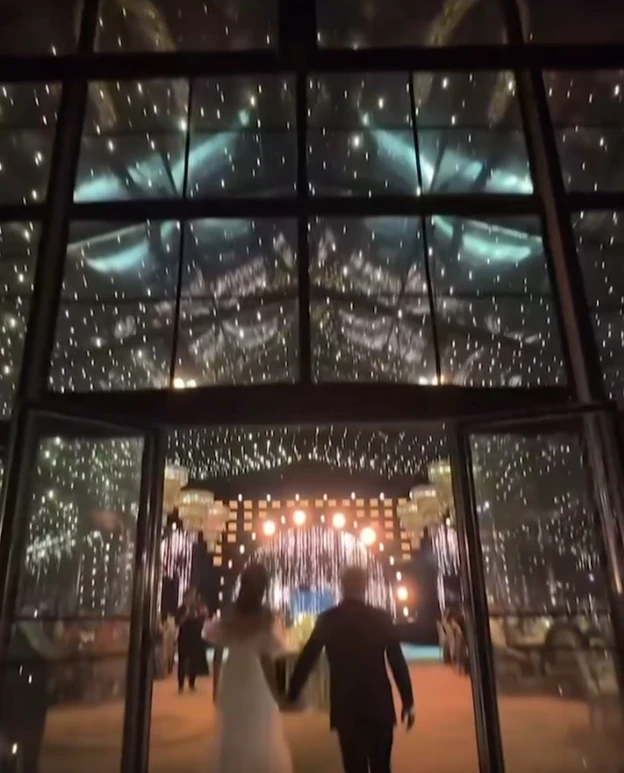 La escena inicial del video parece un fotograma de película: un campo infinito de girasoles abiertos en plena floración y un corredor natural entre las plantas, armado como pasillo de ceremonia. Sobre ese sendero amarillo y luminoso, la pareja camina hacia un altar sencillo, integrado al paisaje y pensado para que la naturaleza domine la imagen.

La luz del atardecer realza todo: el dorado del campo, el movimiento suave de las flores y la intimidad del momento. No hay estructuras pesadas ni elementos que compitan con el entorno. La apuesta es clara: dejar que la naturaleza sea el decorado.

Este tipo de ceremonias inmersivas, donde el escenario natural se convierte en parte del ritual, gana cada vez más terreno entre parejas que buscan autenticidad, emoción y simplicidad estética. El campo de girasoles aporta, además, un simbolismo potente: vitalidad, alegría y una idea muy poética de “buscar la luz”.

Una fiesta bajo techo vidriado: el jardín de invierno que dejó a todos sin palabras

Tras la ceremonia, el video muestra un segundo escenario igual de impactante: un jardín de invierno gigante, montado especialmente para la fiesta. Se trata de una estructura completamente vidriada, con paredes y techo transparentes que permiten ver el cielo nocturno desde adentro.

La iluminación cálida, a base de microleds y guirnaldas, crea un clima íntimo y elegante. Las mesas -tanto largas como redondas- están decoradas con flores blancas y verdes, velas y vajilla neutra. Todo pensado en clave natural, sin recargar, manteniendo la armonía con lo que ocurrió horas antes en el campo.

La gran virtud del espacio es que combina protección y aire libre: desde adentro se ve el cielo estrellado como si no hubiera techo, pero con la comodidad y el resguardo de un salón diseñado para una noche especial. El efecto es cinematográfico.

El cielo como protagonista y un cierre con fuegos artificiales

En los tramos finales del video, el techo vidriado funciona como pantalla: el cielo oscuro, las estrellas y el brillo del exterior se integran al ambiente. La fiesta transcurre literalmente “bajo las estrellas”, en un escenario que mezcla naturaleza y diseño sin perder calidez.

El cierre llega con fuegos artificiales en tonos dorados y blancos, ubicados a una distancia segura del salón. Reflejan su luz sobre los paneles del techo y generan un efecto envolvente, delicado y festivo. Es un final que potencia el clima emocional de toda la celebración.

Por qué estas bodas inspiran tanto

Las bodas como esta combinan tres elementos que conectan con una búsqueda contemporánea:

Rituales auténticos, donde los protagonistas se sienten parte del paisaje.

Experiencias sensoriales, donde la luz, el entorno y la atmósfera importan tanto como la decoración.

Naturaleza + diseño, en equilibrio, sin exageraciones y con intención clara.

La boda chaqueña ya circula por redes como ejemplo de una tendencia que crece: celebrar en escenarios que cuentan una historia, sin necesidad de grandes producciones, sino priorizando el entorno, la identidad de la pareja y la magia del momento.