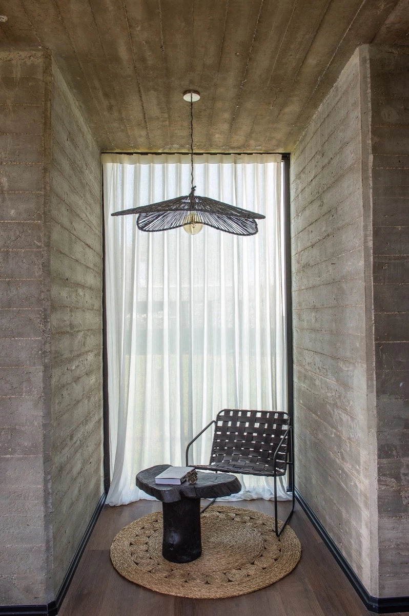 Un rincón de lectura, con un sillón de un cuerpo de lana bouclé que dialoga con una lámpara de fibras.