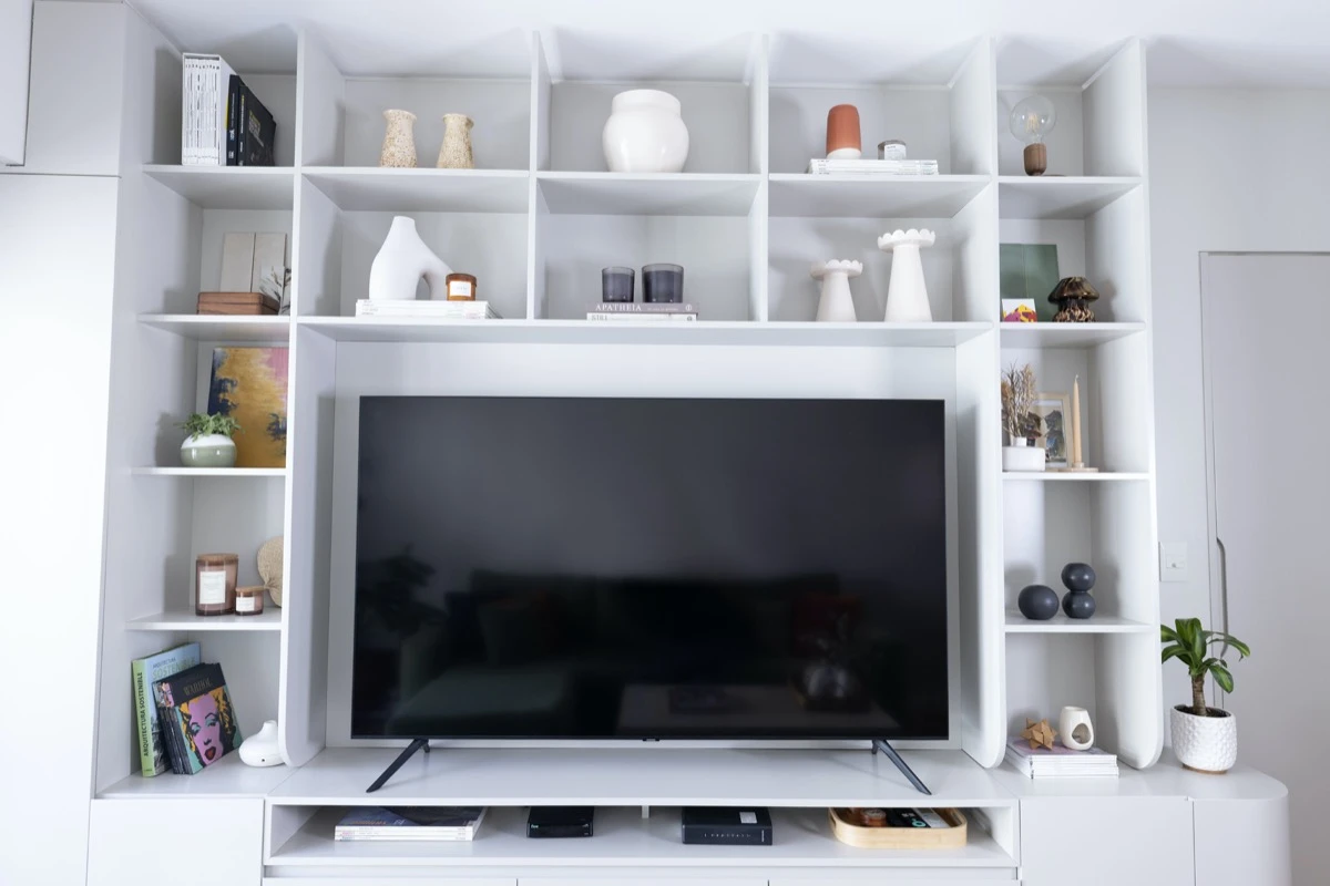 Para la tevé, la arq. Laura Novo (@lmn.estudio) diseñó un mueble/biblioteca a medida, en un laqueado semi mate y con estantes en gris suave.  