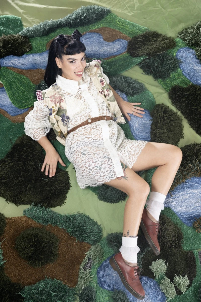 Yael Tesouro recostada sobre sus creaciones verdes (mini biomas) entre las que caminaron las modelos que desfilaron en Feria Puro Diseño 2025.