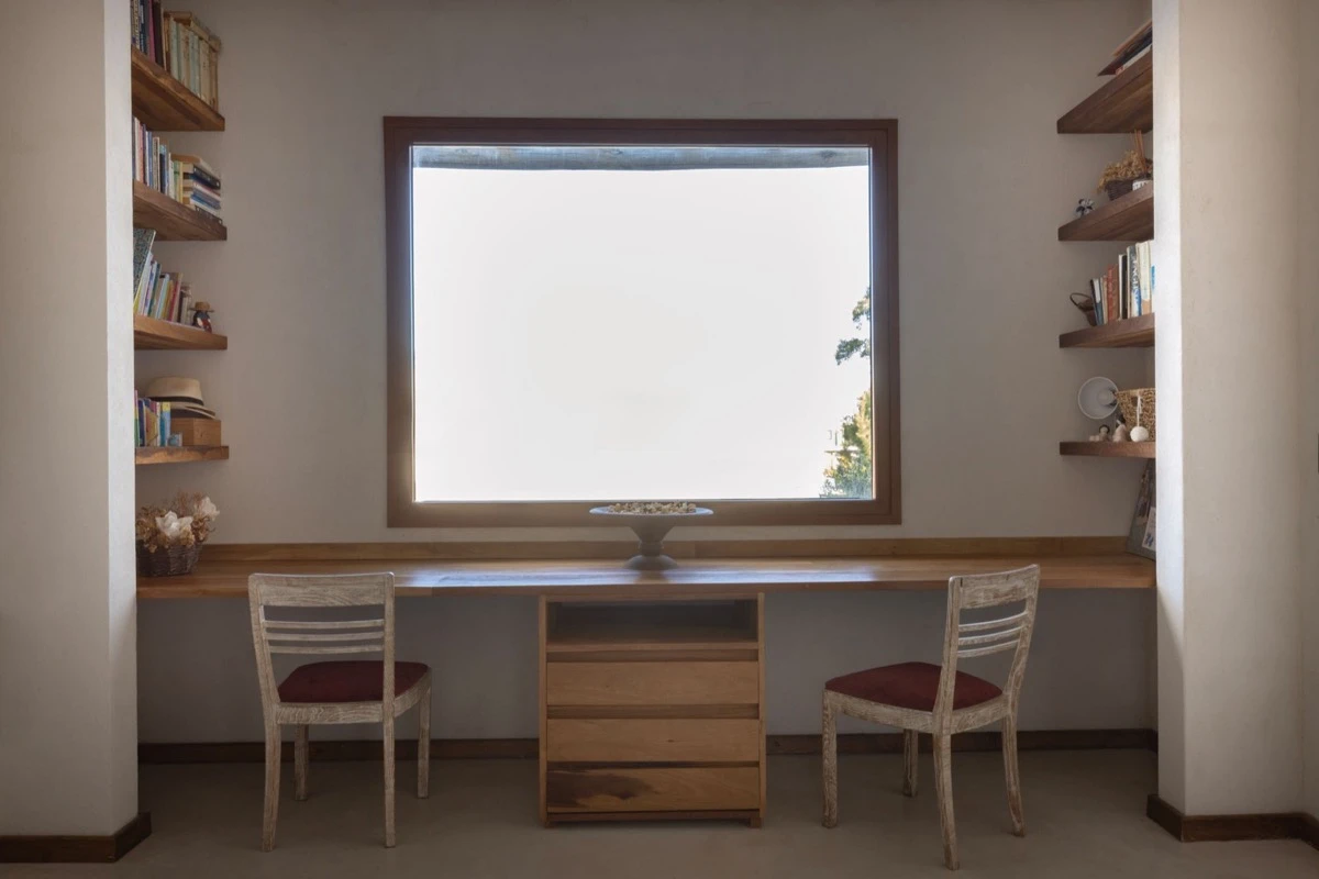 El escritorio, ubicado al subir las escaleras, se planteó como un rincón funcional y sereno con vistas hacia un gran ventanal que baña el ambiente con luz natural. 