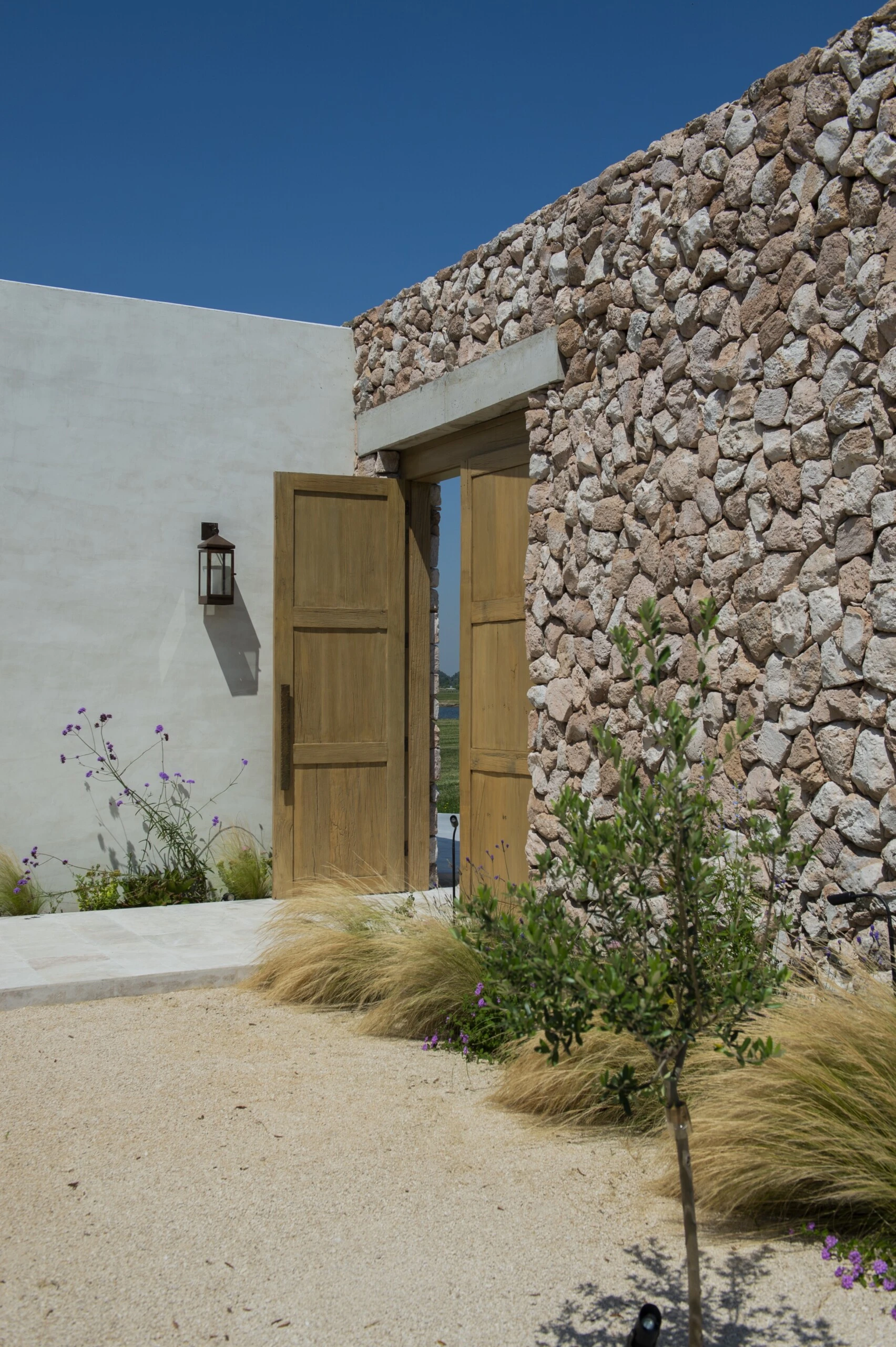 Ese muro no solo ordena y jerarquiza: crea un patio de acceso contenido, íntimo, 